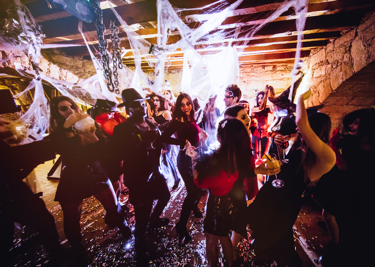 Young friends dressed-up in Halloween costumes dancing at dance party