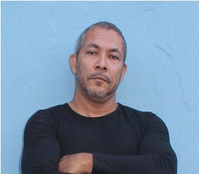 Noin Rivera stands in front of a blue wall