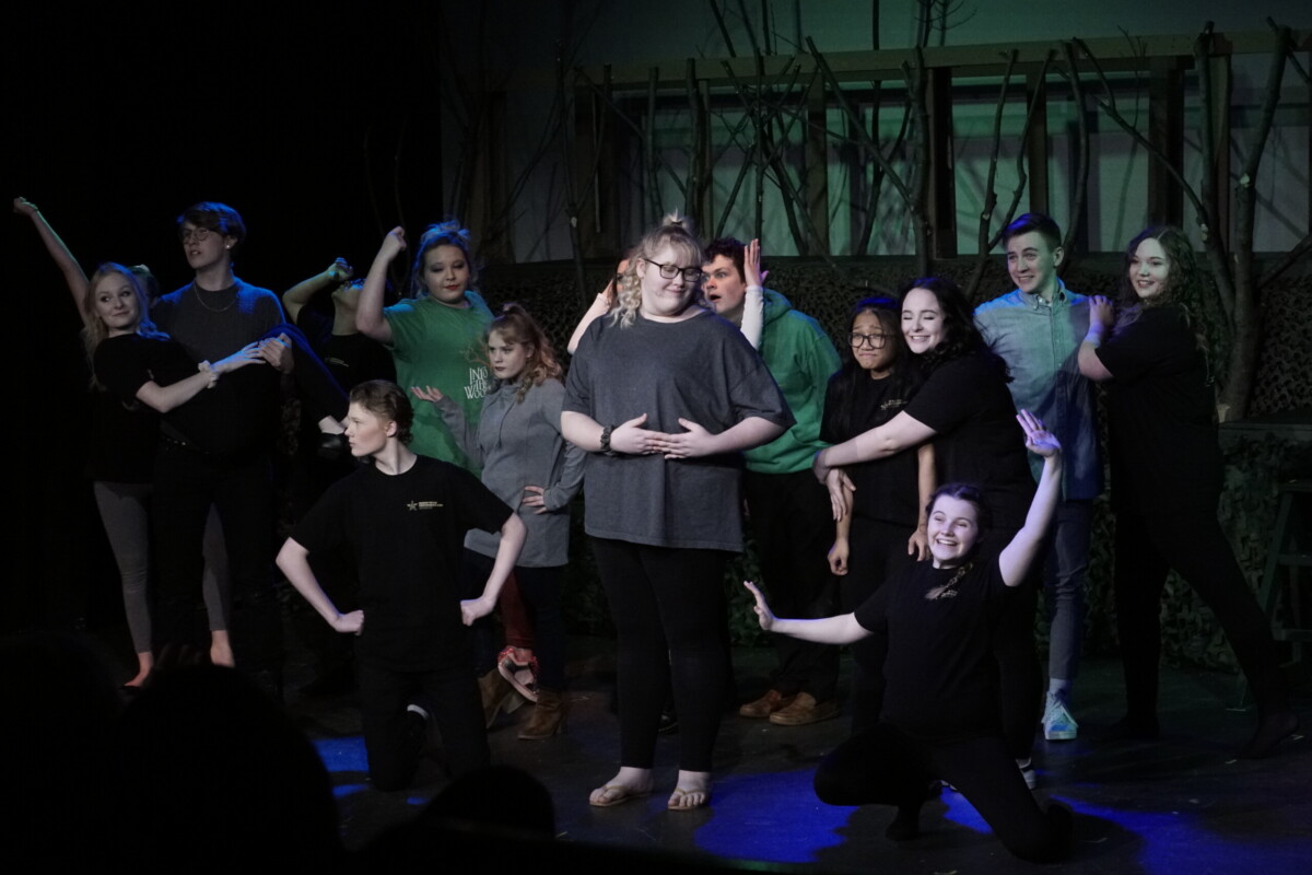 Students pose on stage in a group performance